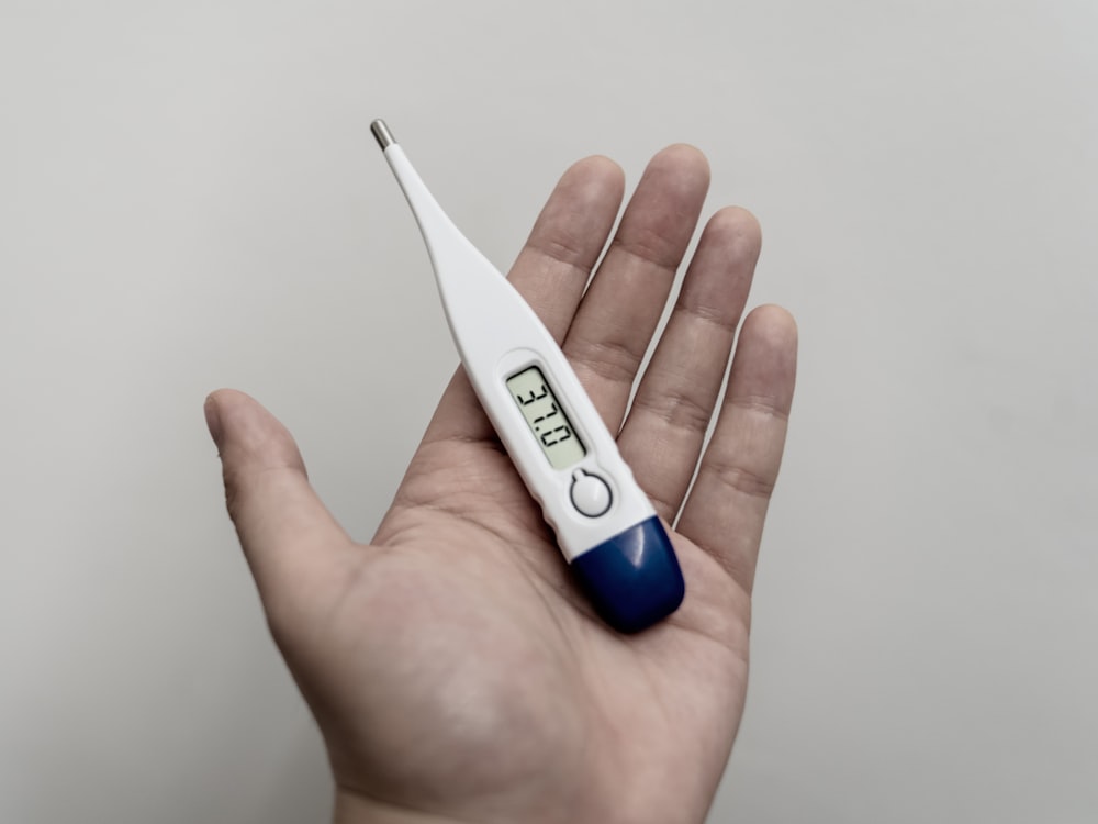A sick person holding a thermometer before getting a doctor’s note online
