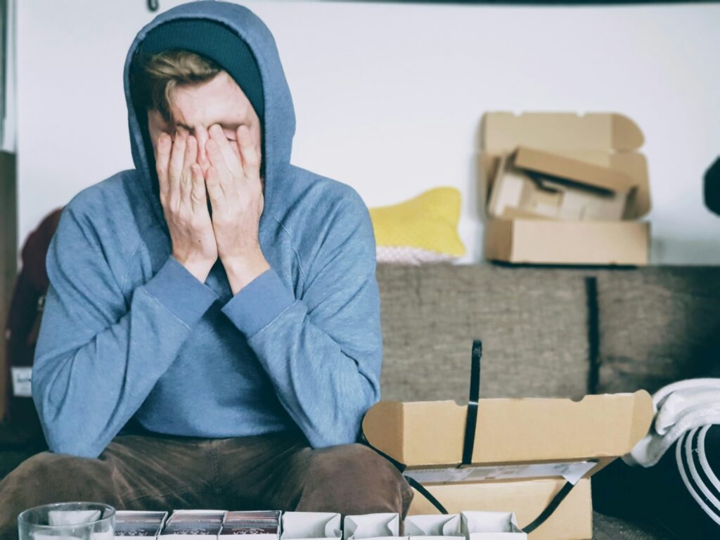 Man sitting on a sofa with both hands covering his face