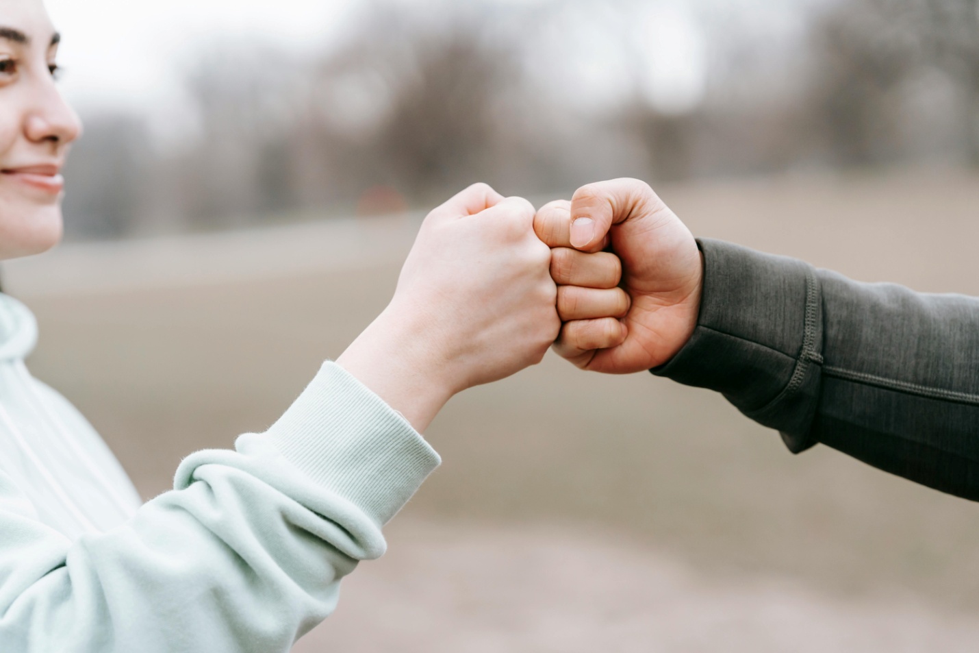 Woman greeting a man by bumping fist while smiling