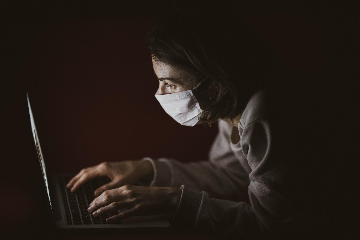  A woman with a facemask using a laptop 