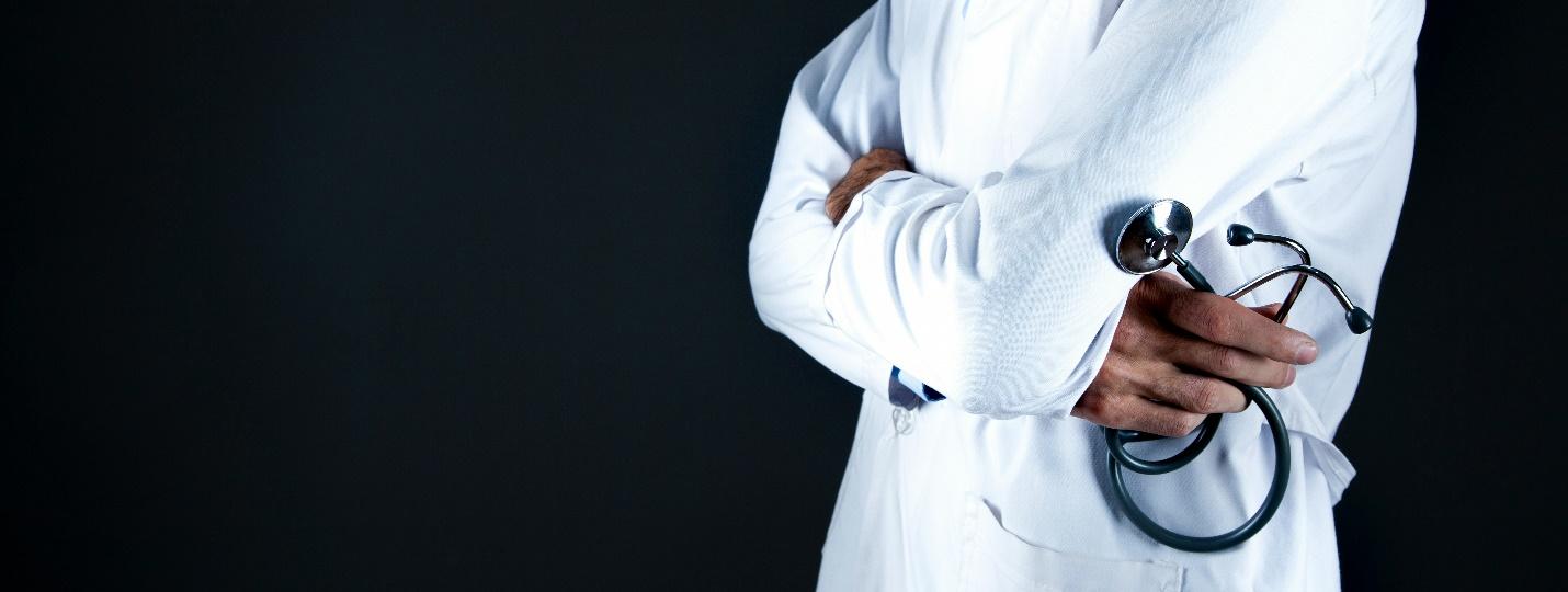 A doctor in a white coat holding a stethoscope 