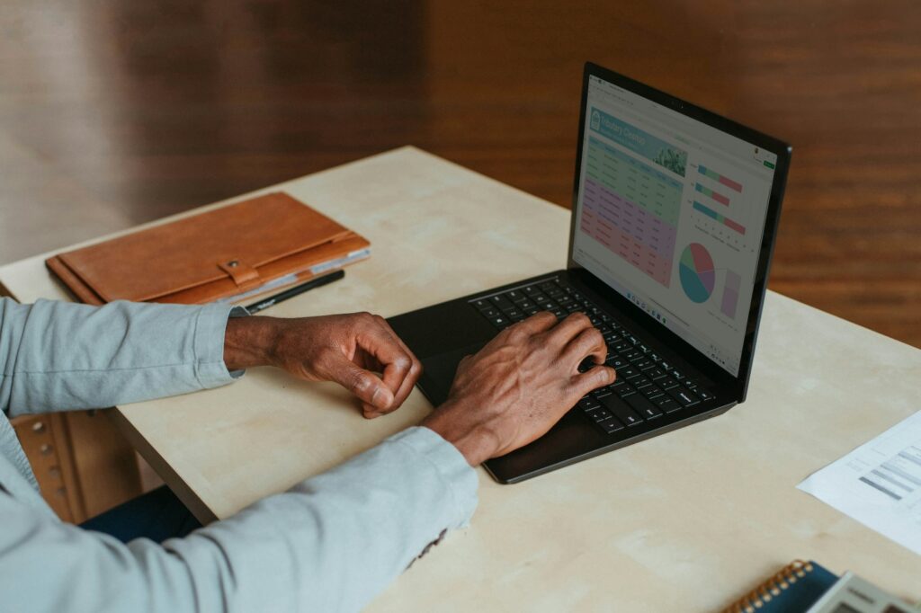 laptop on a table beside a brown notebook