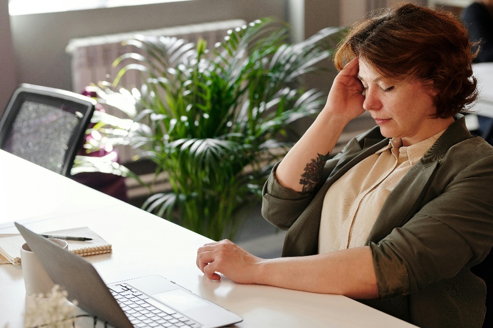 woman sitting in an office with her hand on her forehead