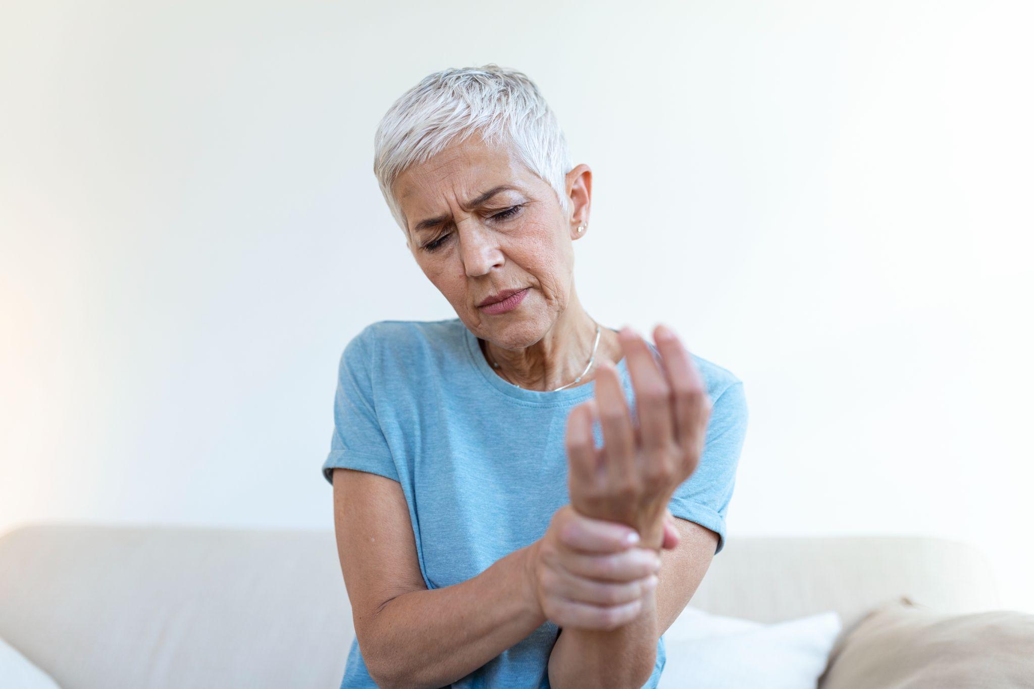 An older woman holding her wrist in pain due to arthritis.