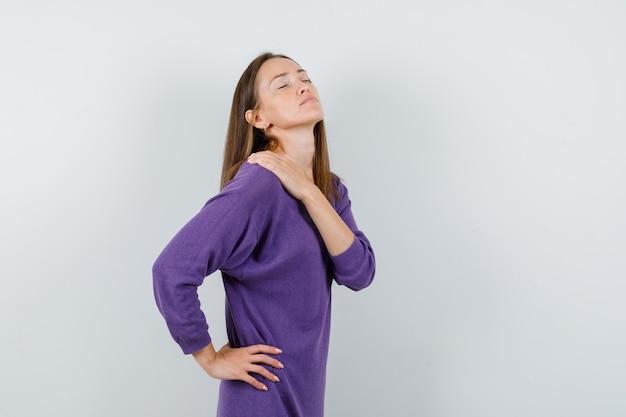 A young woman holding her shoulder in discomfort, representing fibromyalgia.