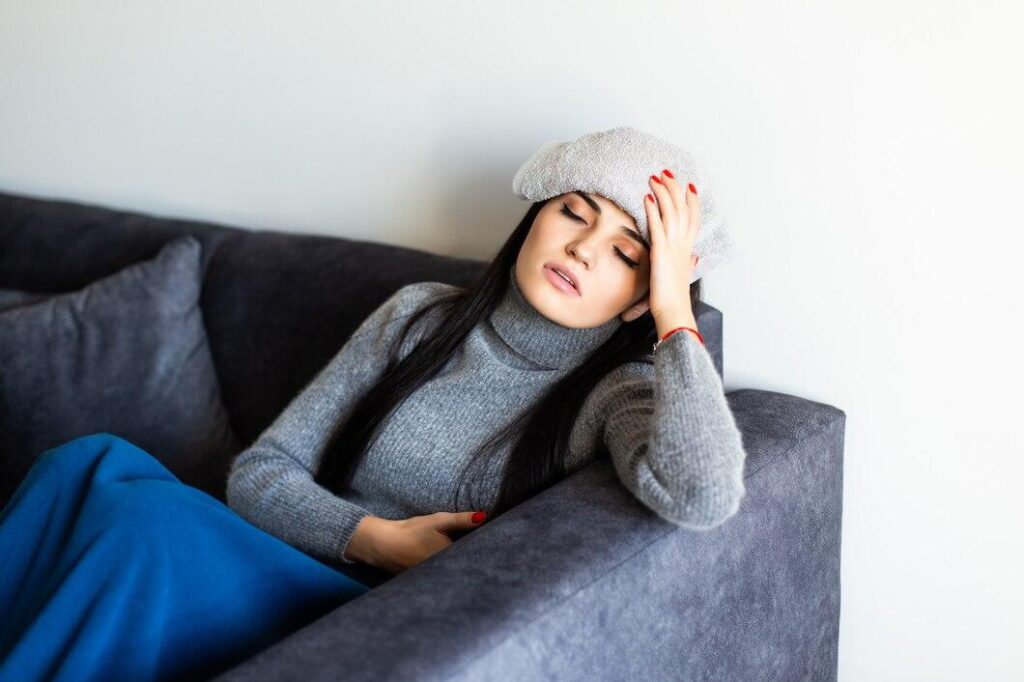 A young woman in a grey sweater sitting on a couch.