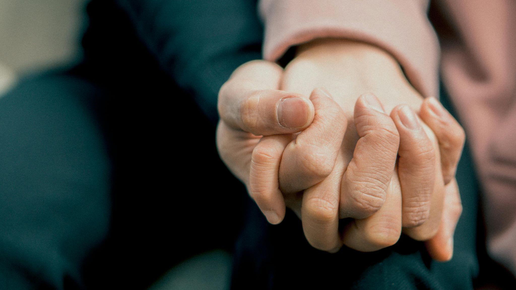 A person holding hands for emotional support 