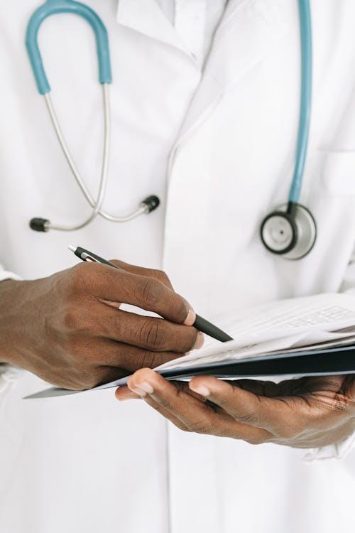 A person in a white coat holding a pen.