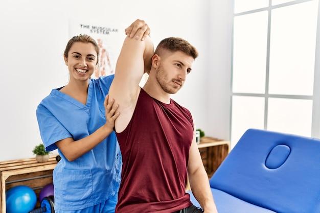 A young Hispanic physiotherapist assisting a man with arm rehabilitation.