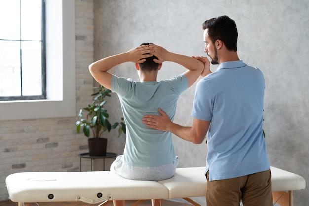 A male physiotherapist assisting a patient during a rehabilitation session for back pain.