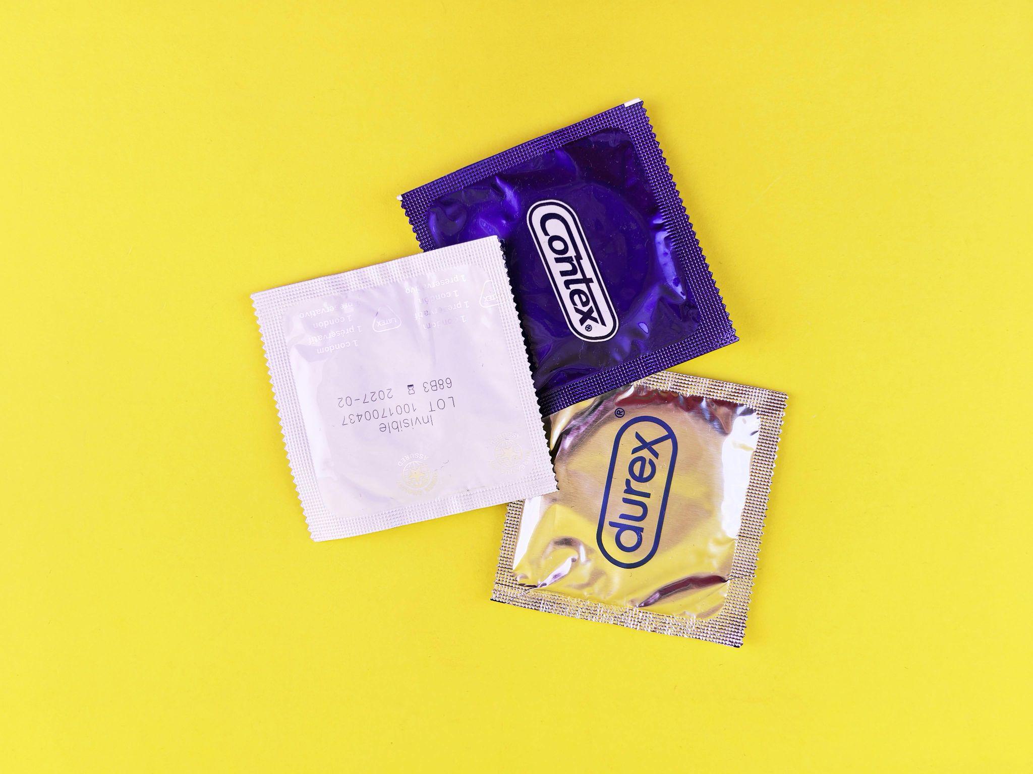 Three different condom packages (Contex and Durex) laid on a yellow background.