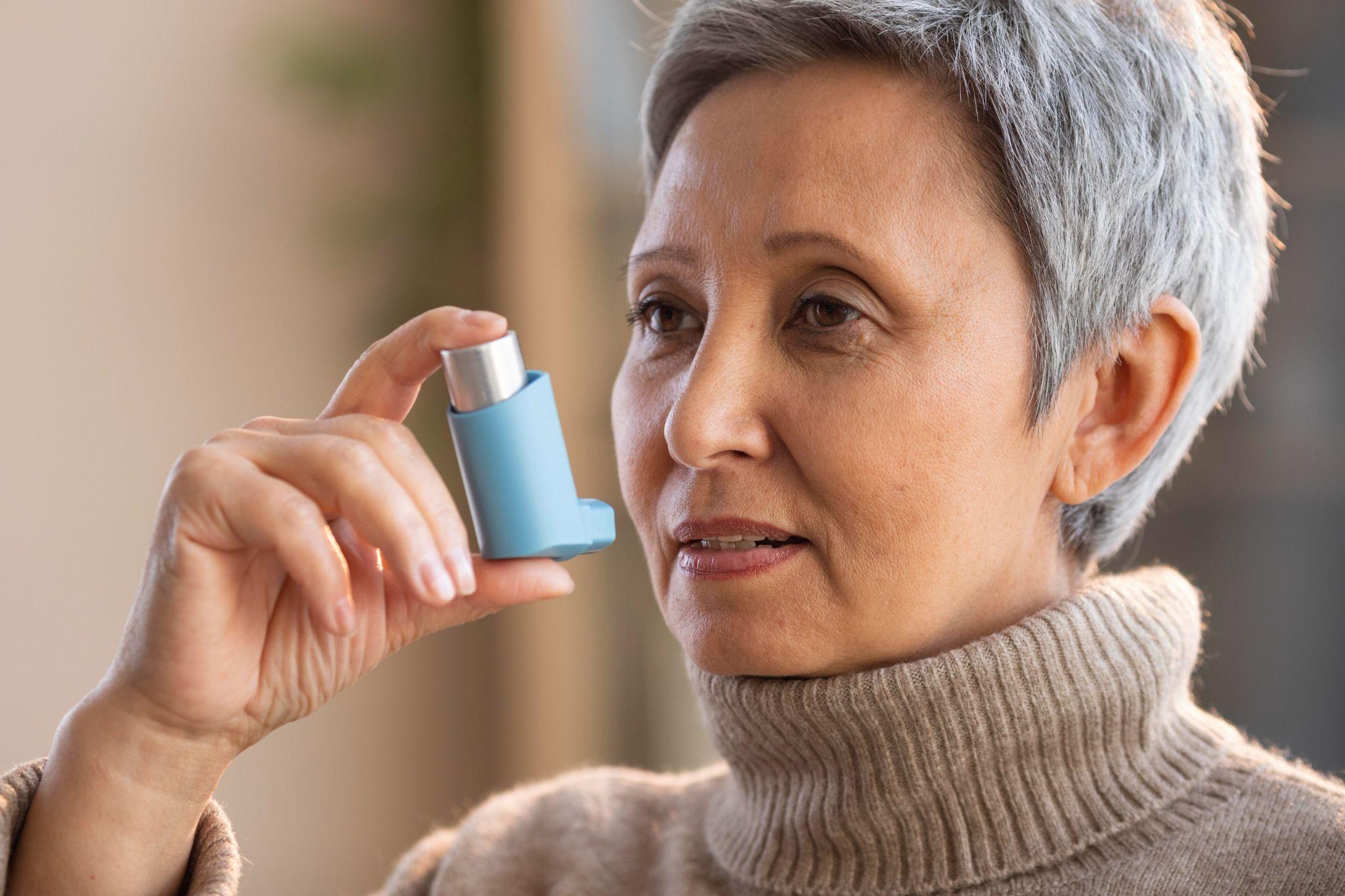 An elderly woman using an inhaler