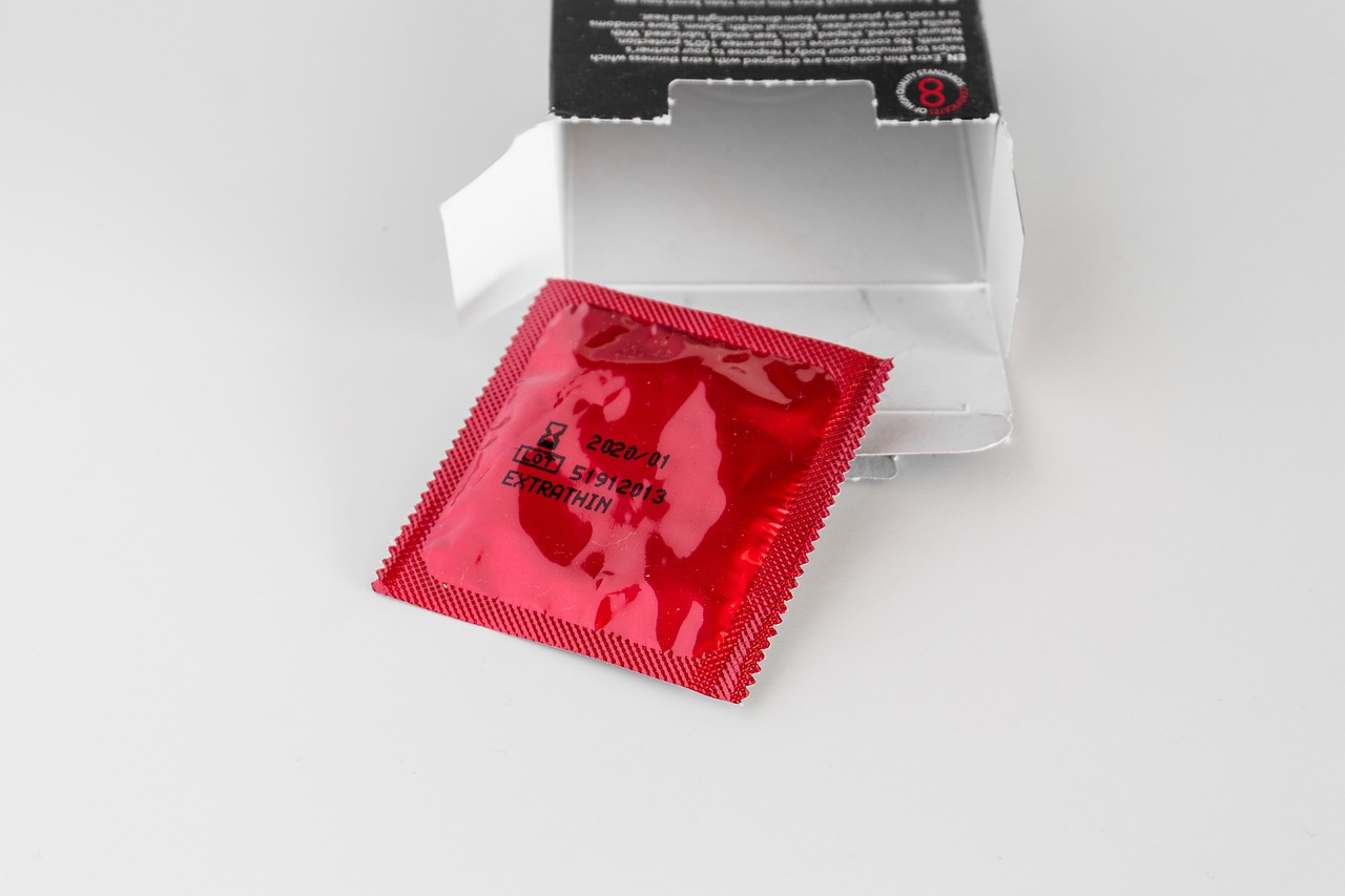 A red condom pack is opened, showing the condom inside.