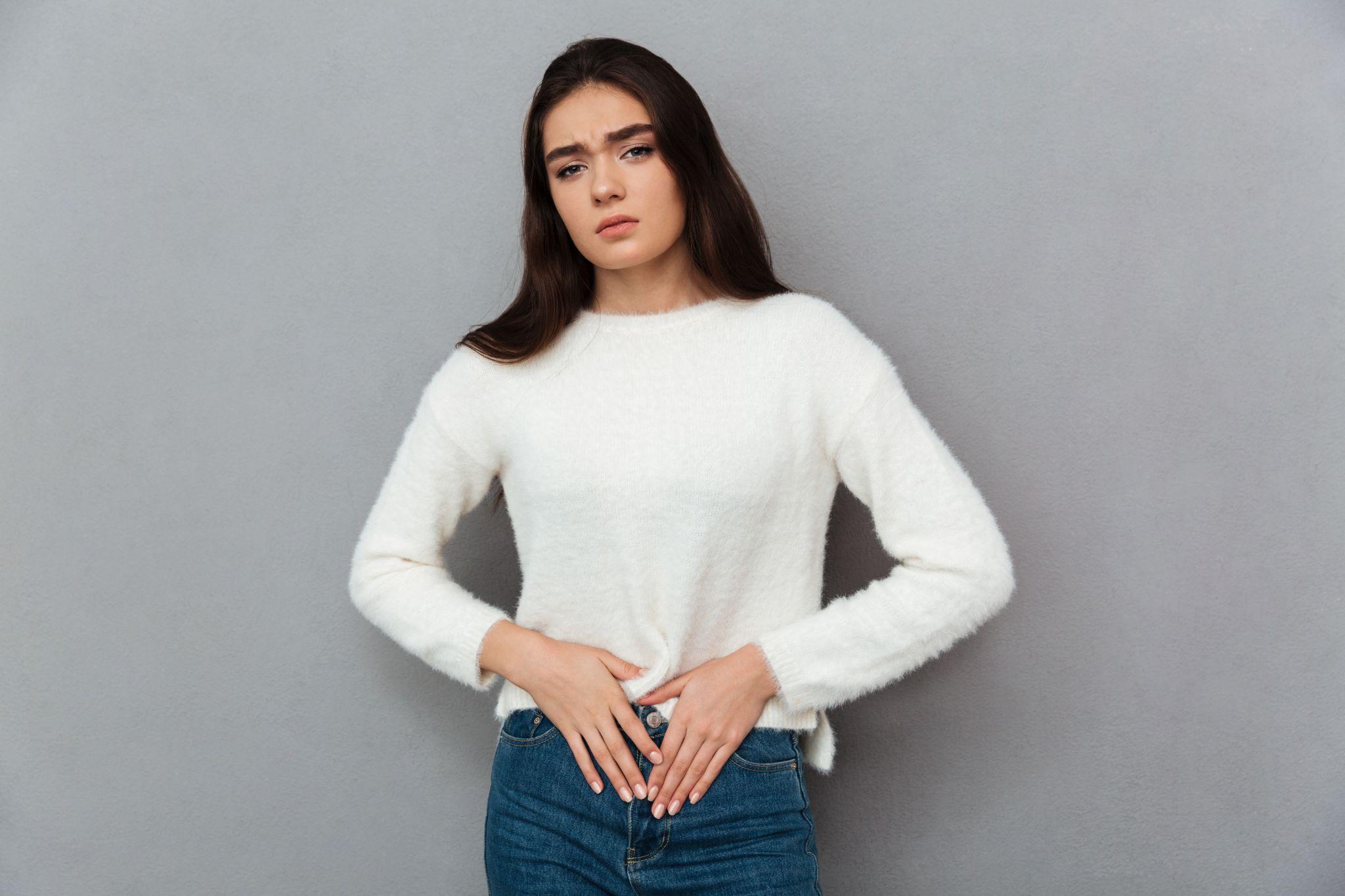 A woman holding her lower abdomen, visibly in pain.
