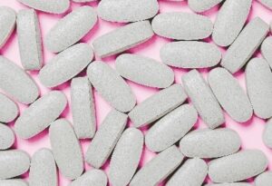 White pills against a pink background 