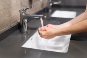 Person washing their hands with tap water 