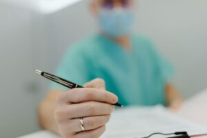 A professional doctor writing something on their writing pad.
