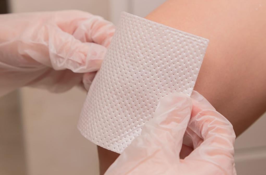 A person putting on a bandage to cover a wound. 