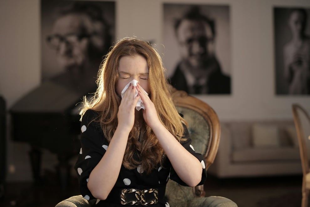 Woman sneezing into a tissue with her eyes closed