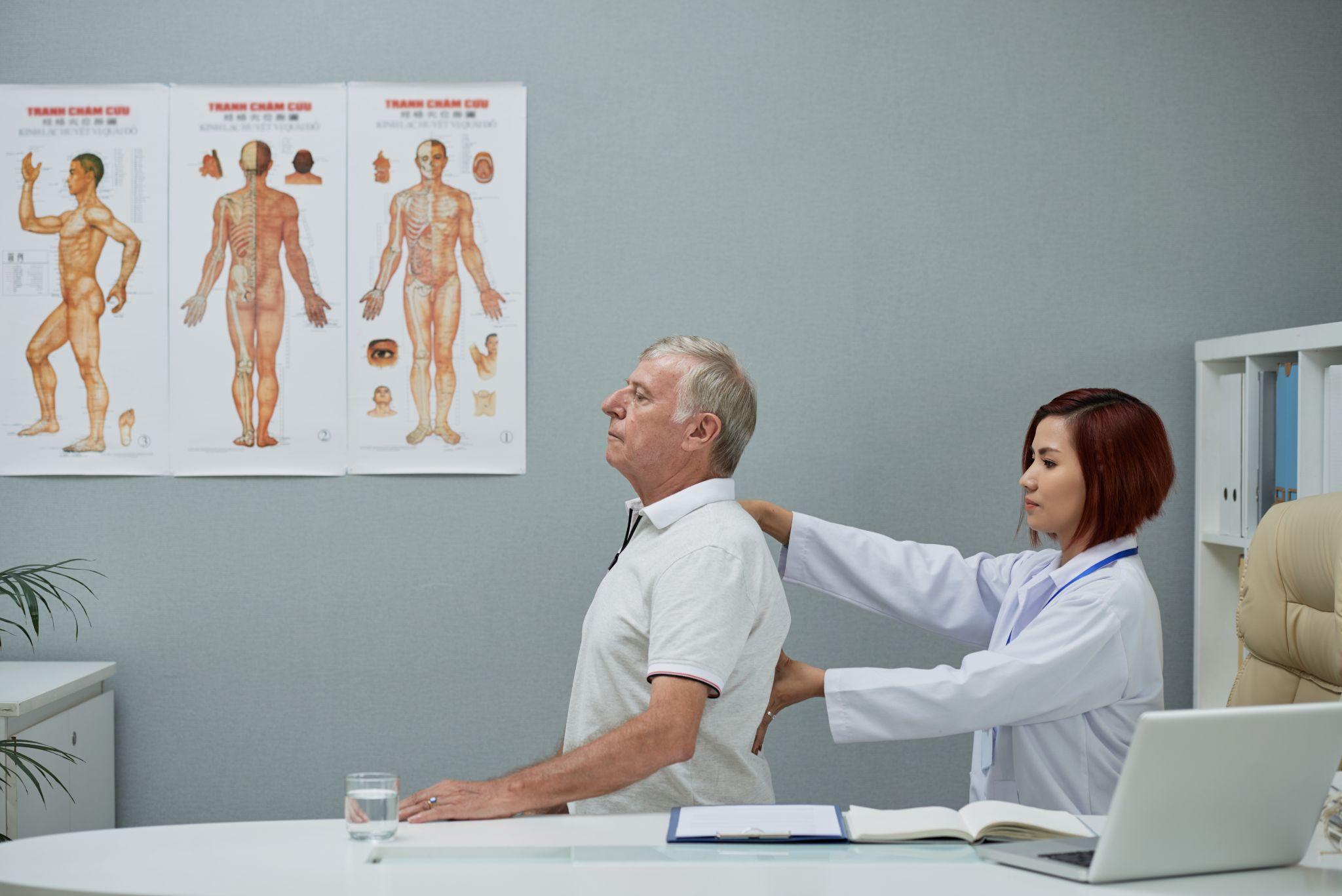 Doctor examining a patient's back during a physical check-up