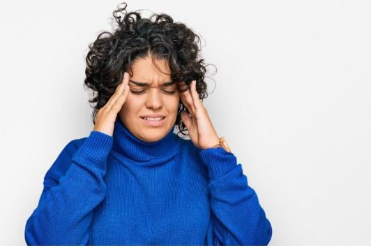 A woman holding her ears in pain.