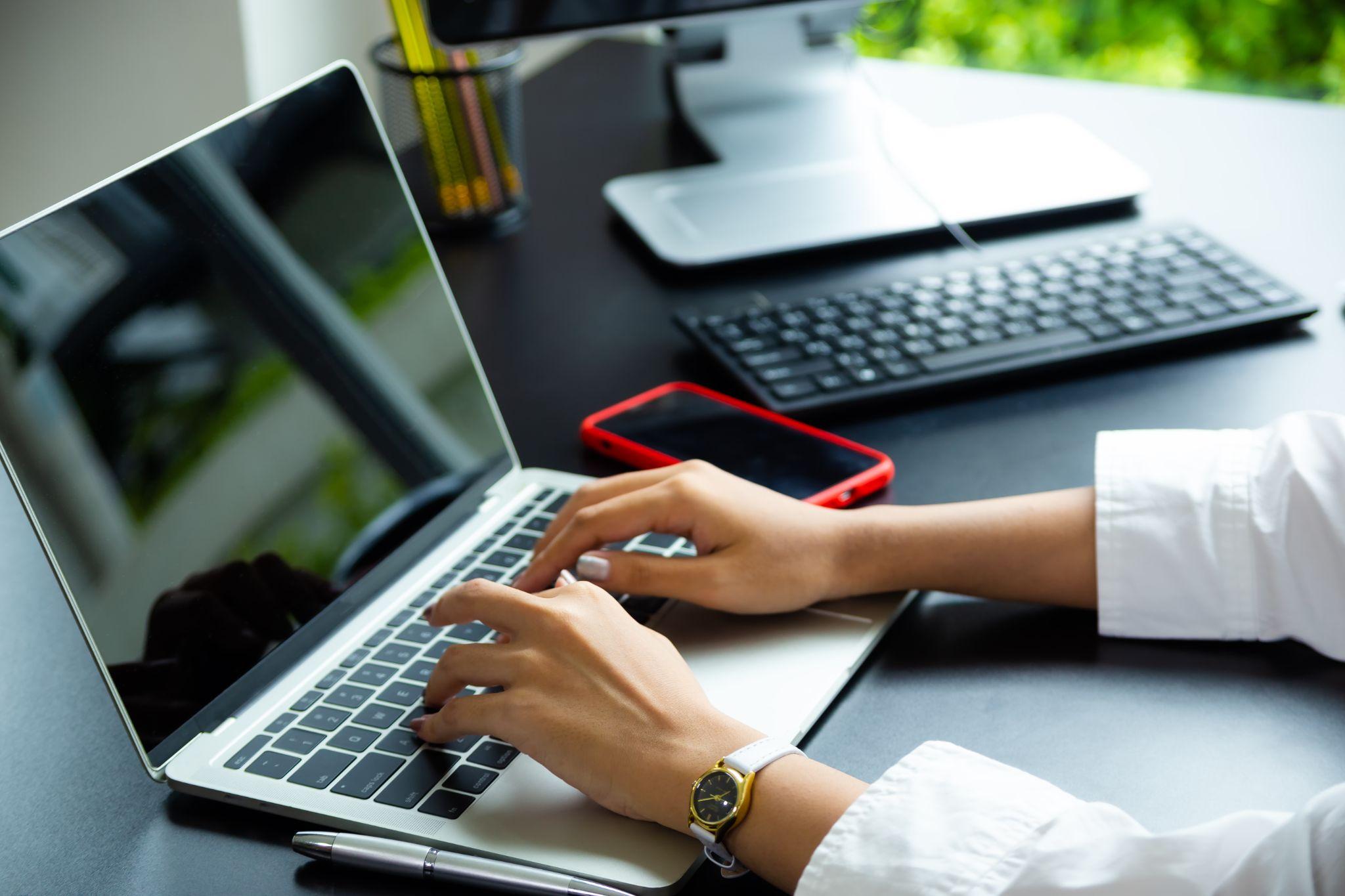 Woman typing on a laptop while wearing a watch