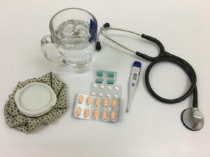 Thermometer, water, medicine, and a stethoscope next to a glass used when arranging a medical certificate for leave