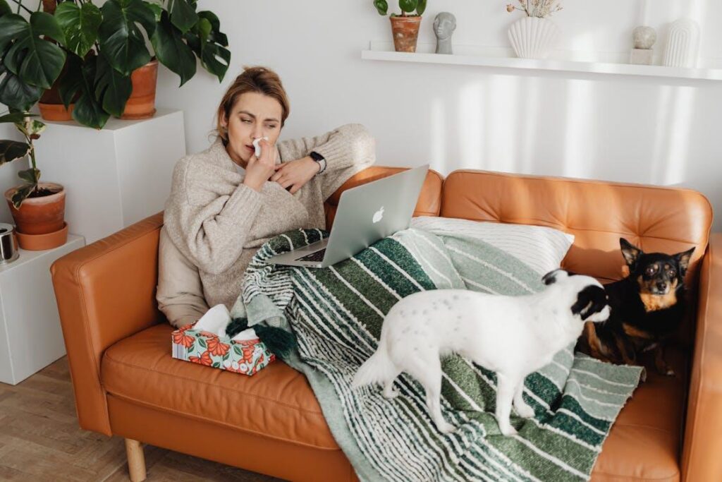 Woman resting on couch with laptop and tissues while considering an online doctor's note for work