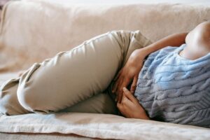 Woman lying on couch holding stomach in pain