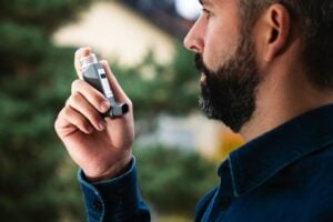 a man using an inhaler for asthma relief outdoors