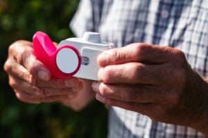 a senior person holding an inhaler device outdoors