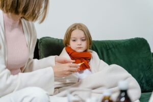 Young child wrapped in a blanket receiving care from an adult.