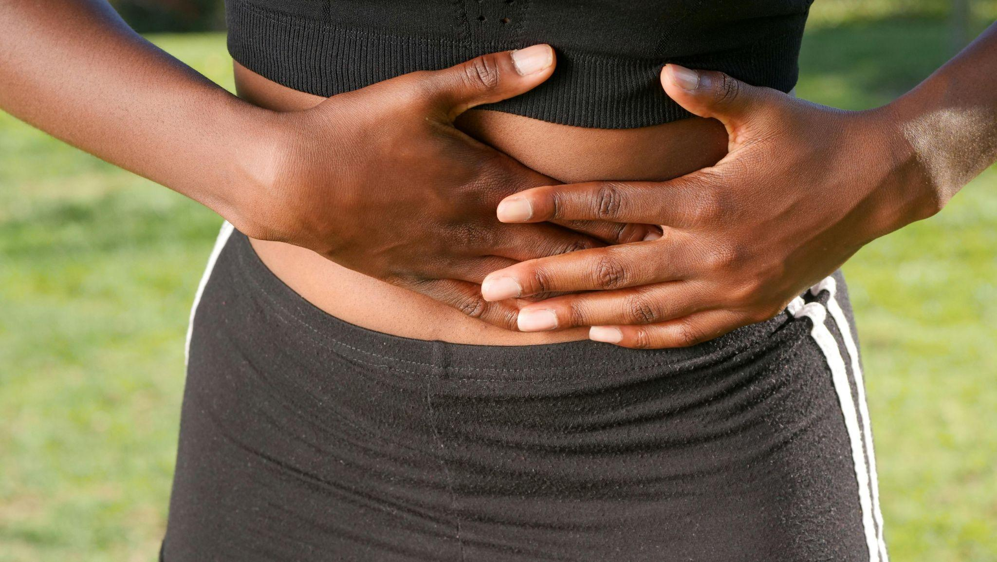close-up of hands pressed against the lower abdomen showing constipation discomfort