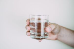 hand offering a clear glass of water