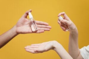 hands spraying sanitizer onto another person’s palm