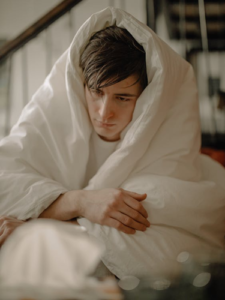 a man keeping himself warm with a blanket. 