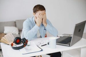 man sitting at a desk with his hands over his face