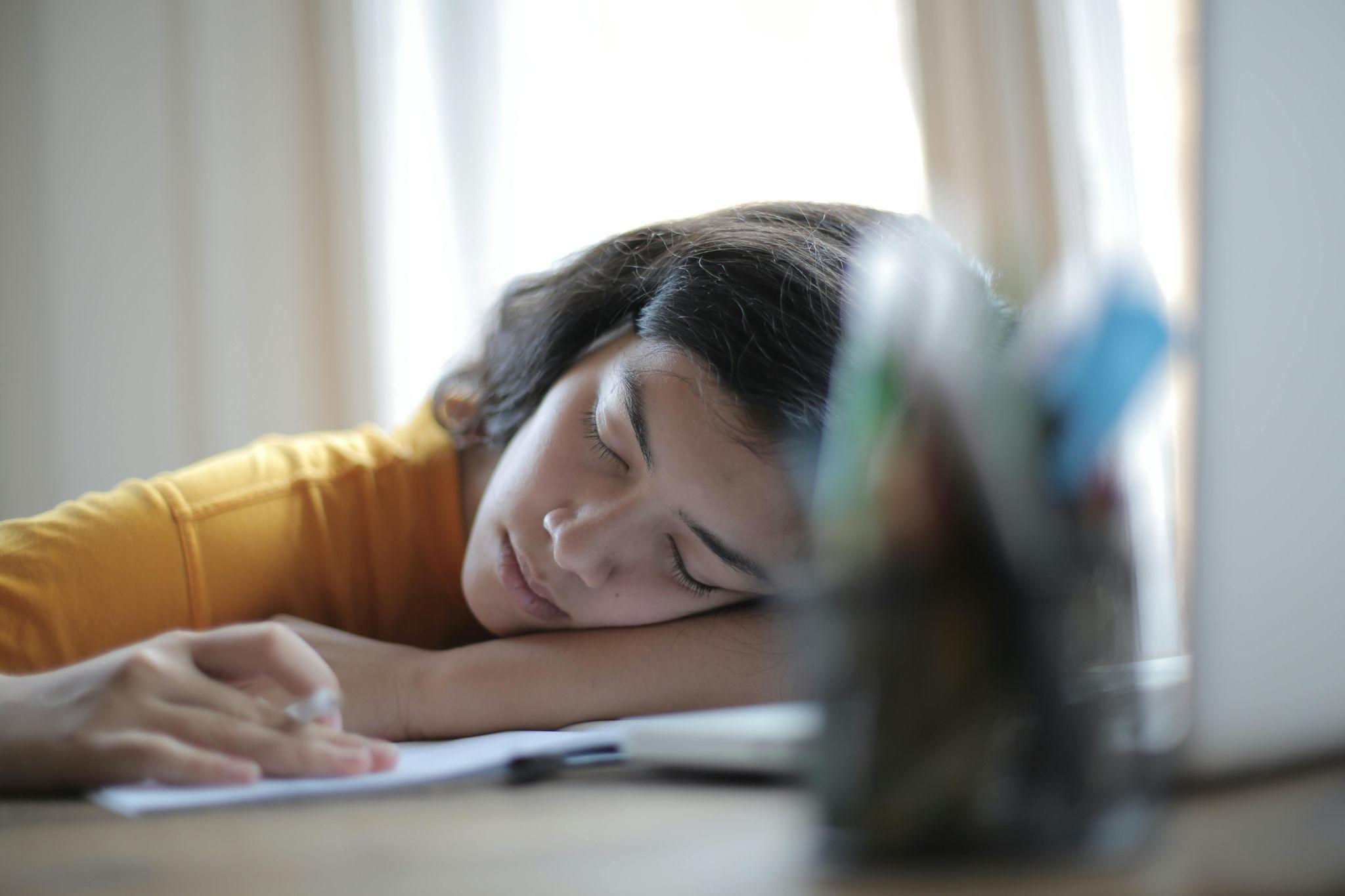 Woman resting her head on her arm, looking fatigued.