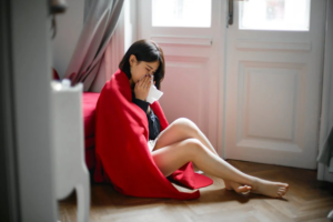 a woman covered with a blanket sitting on the floor.