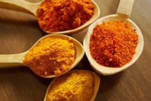 Assorted ground spices arranged in wooden spoons.