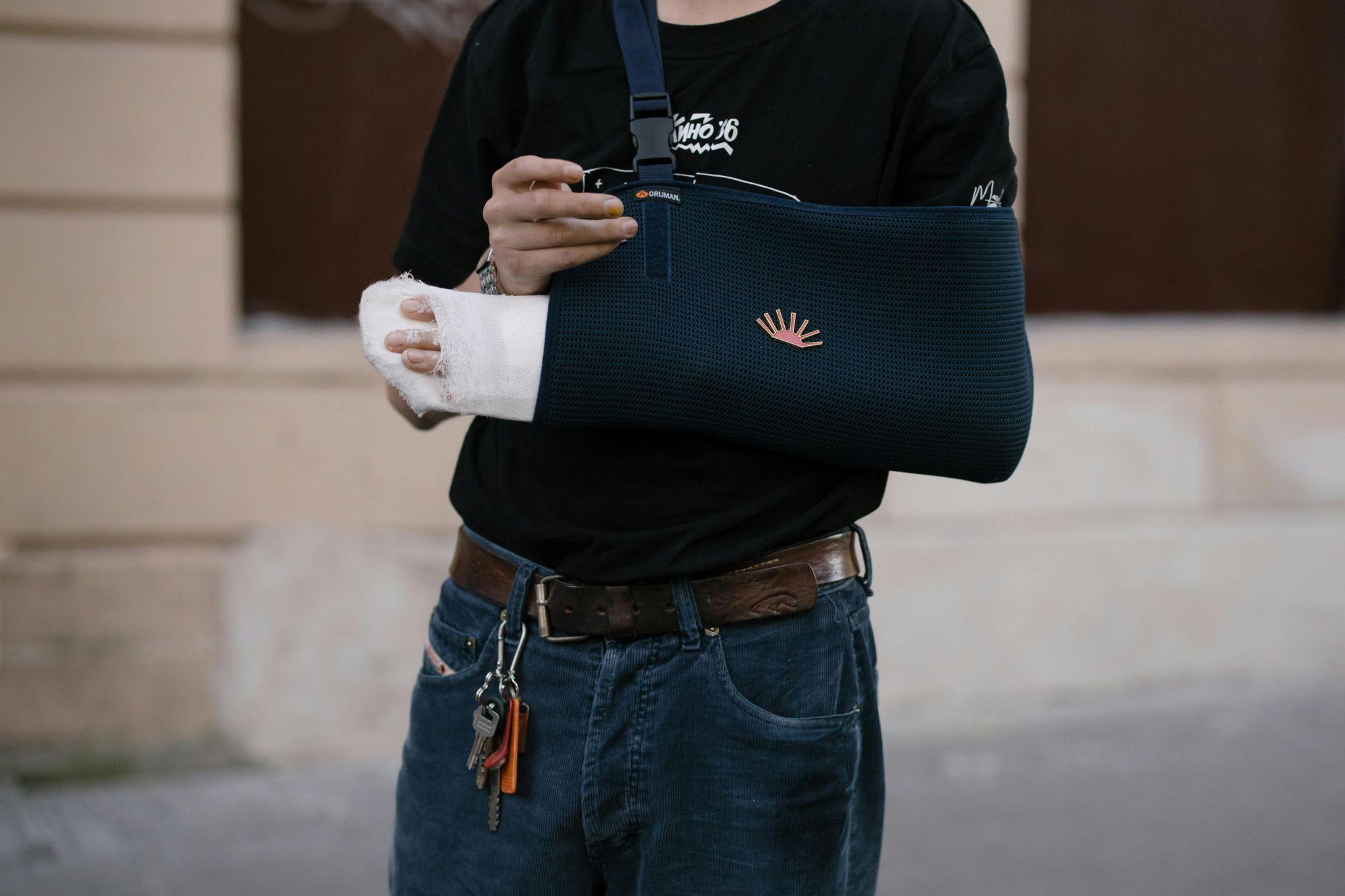 person wearing arm an sling and holding a bandaged hand