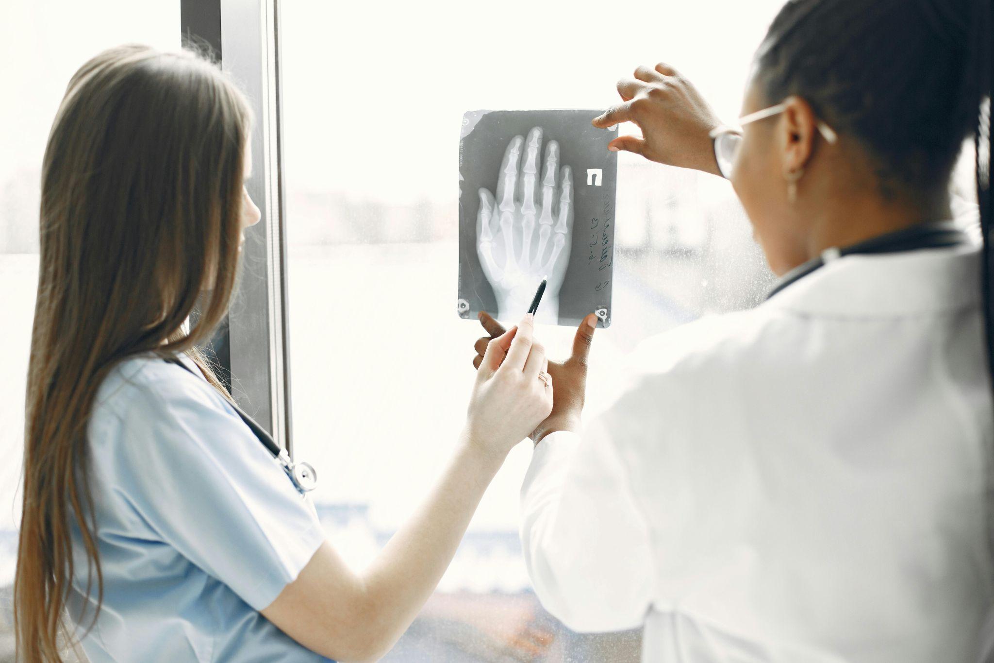 two clinicians reviewing a hand X-ray near a window