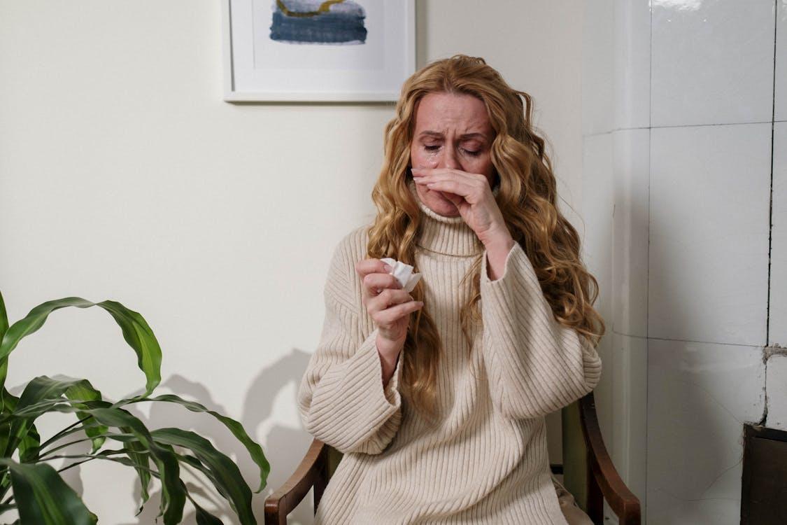 Adult woman holding tissue during allergic reaction symptoms