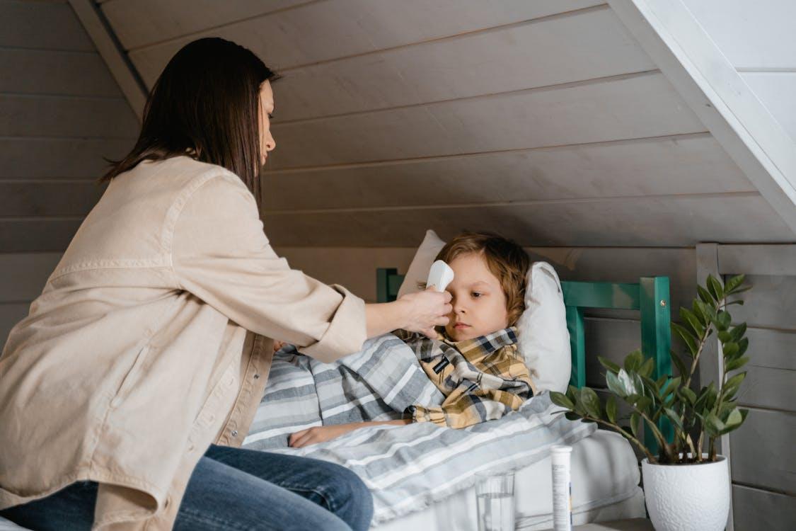 Parent checking a child’s temperature at home while monitoring illness symptoms