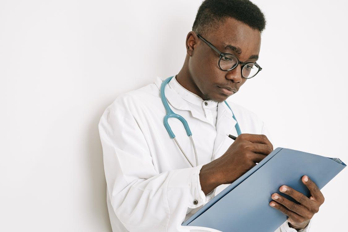 Doctor writing notes on a clipboard for medical absence documentation.