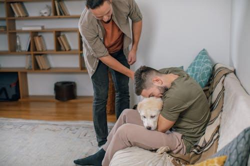 A man cuddling his dog on a sofa