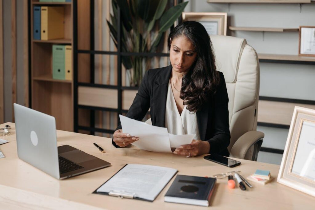 A woman in business attire reviewing documents at an office desk