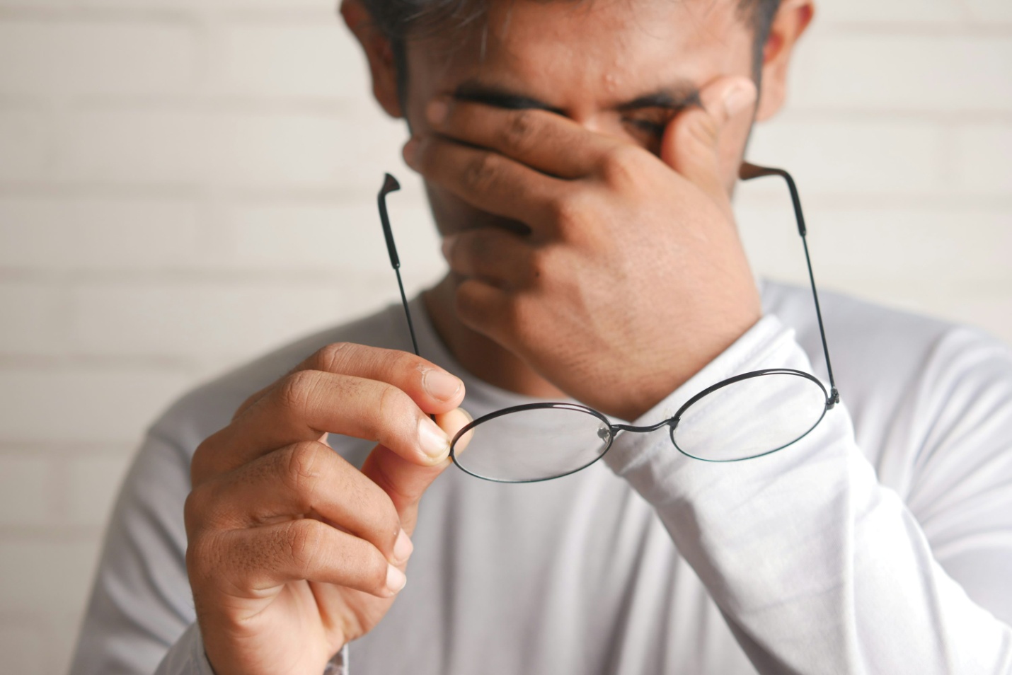 A man taking off his glasses to rub his forehead 