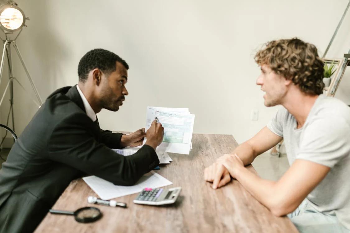 A financial advisor discussing paperwork with a client at an office desk