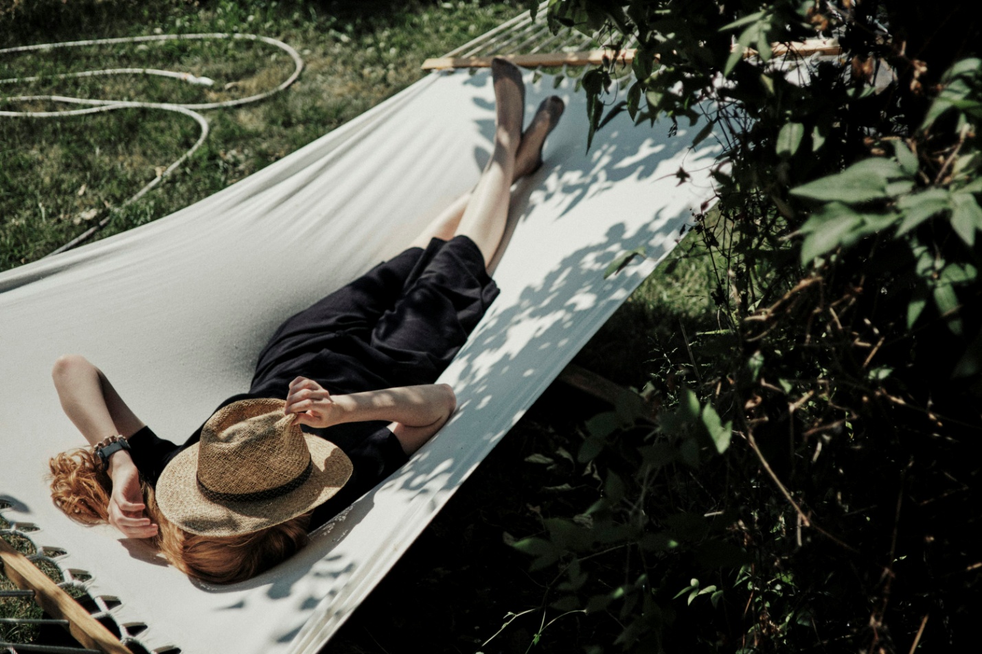 A man lying in a hammock with a hat on 
